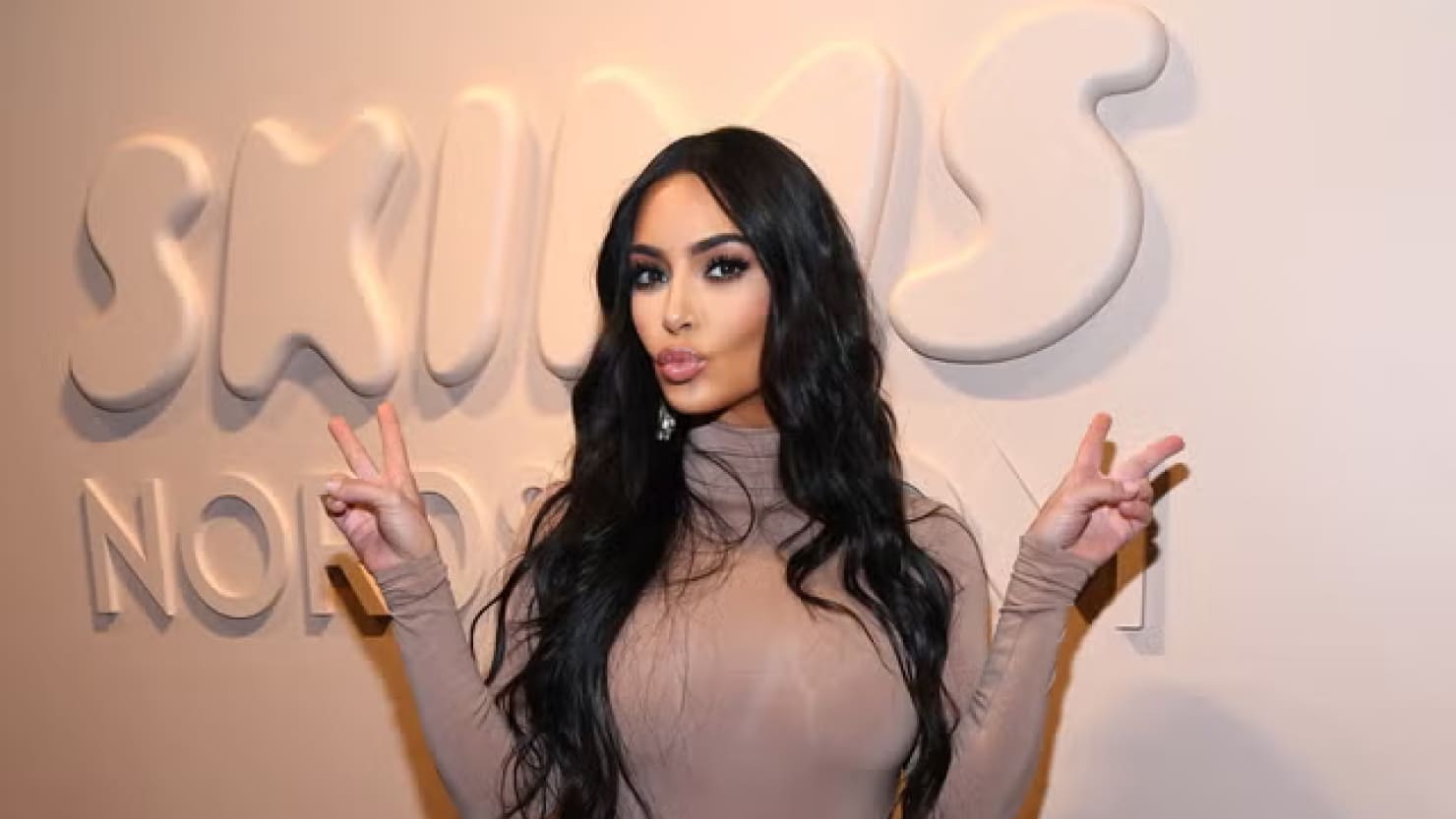 Kim standing in front of her brand's SKIMS logo