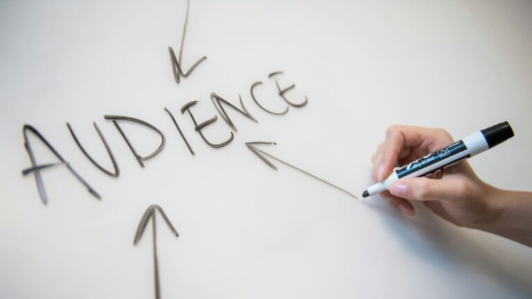 hand writing the word audience on whiteboard